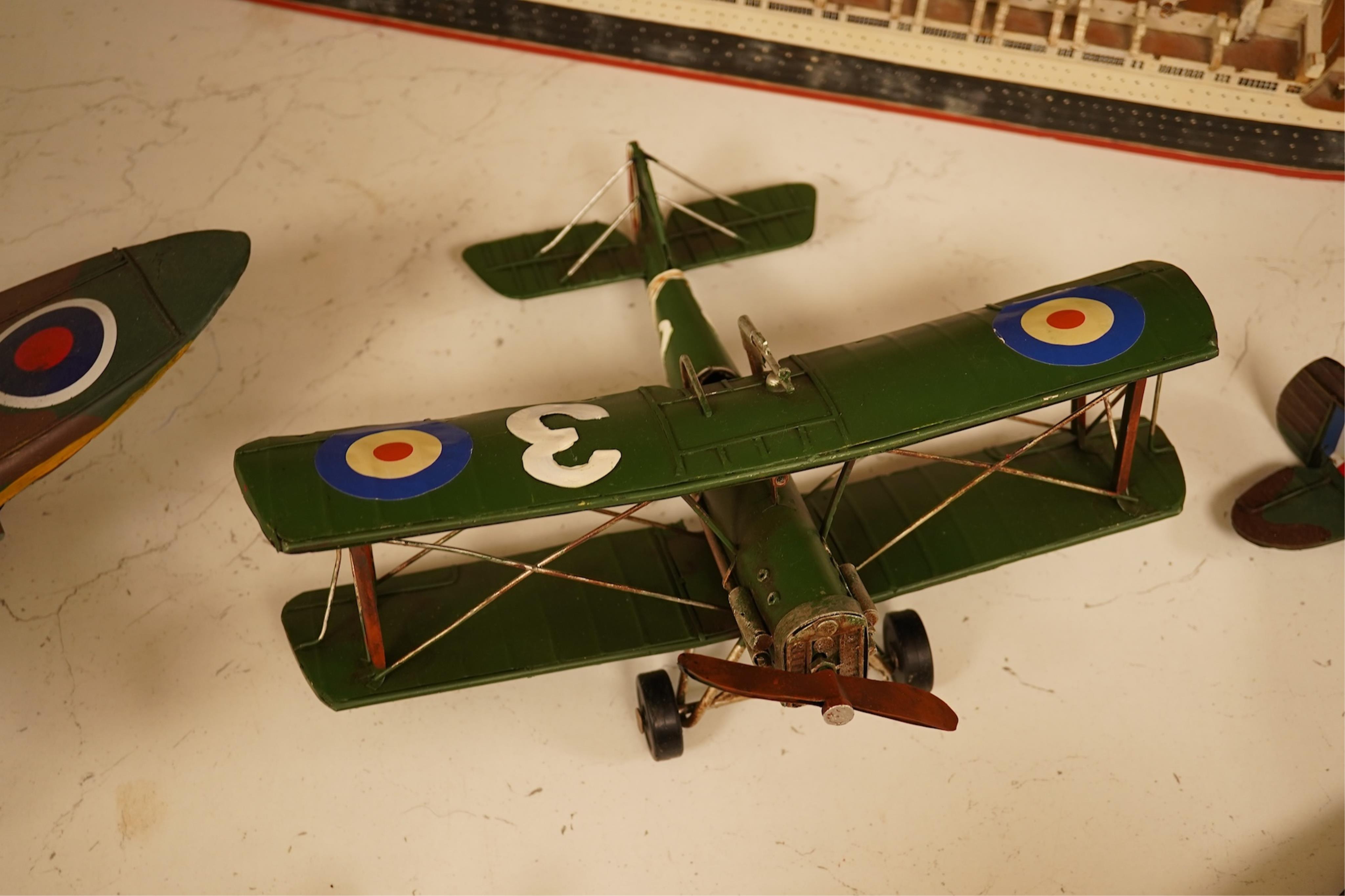 Five decorative metal models of military aircraft, including two Supermarine Spitfires, two First World War, British bi-planes, a German Albatros D.III bi-plane, and a wooden model of RMS Queen Mary, hull 77cm long